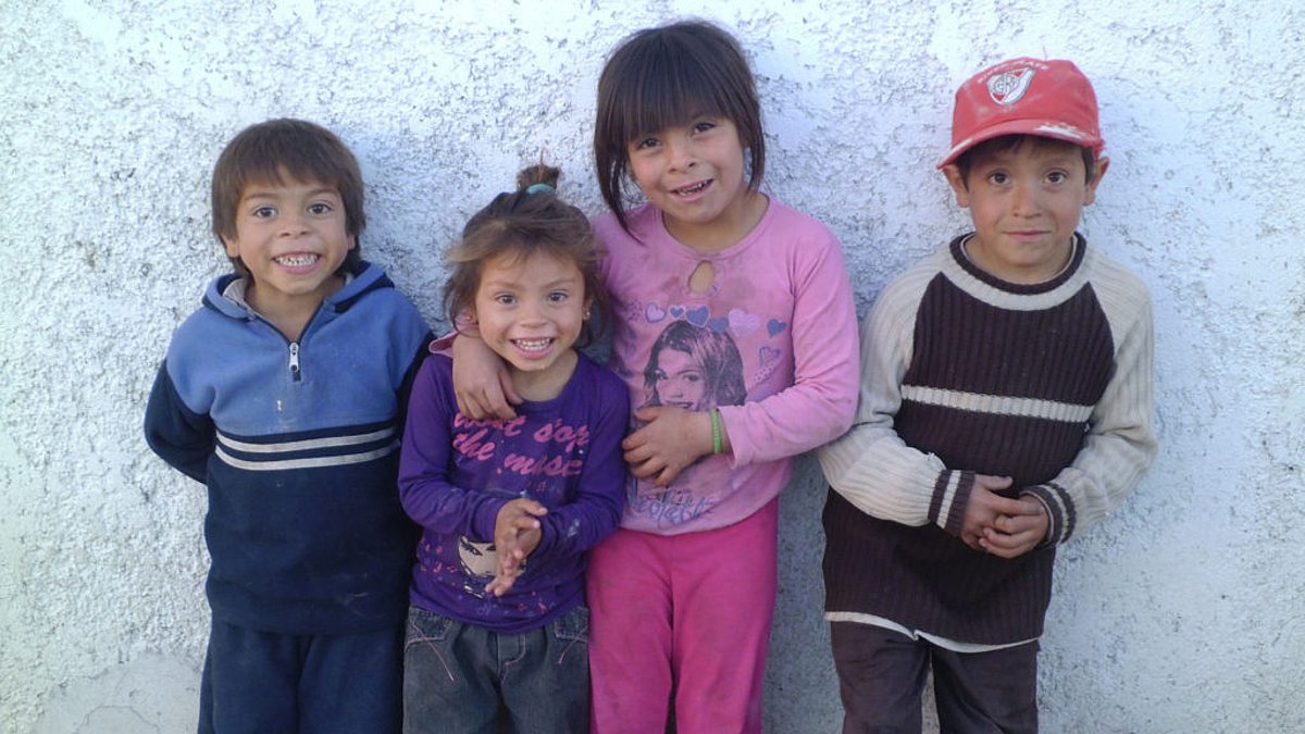 Vier Kinder aus Peru stehend lächelnd vor einer weißen Wand