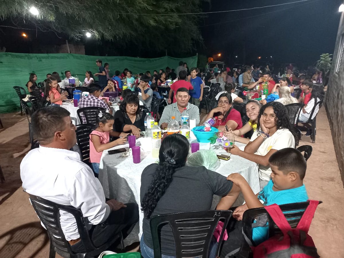 Viele Menschen sitzen am dunklen Abend an großen Tischgruppen zusammen